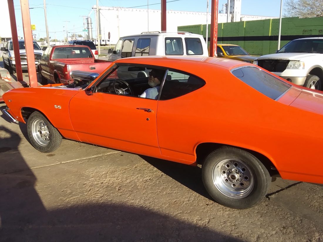 Bright orange Chevrolet Chevelle SS parked at Rob's Garage in Hutchinson, Kansas, with the owner behind the wheel